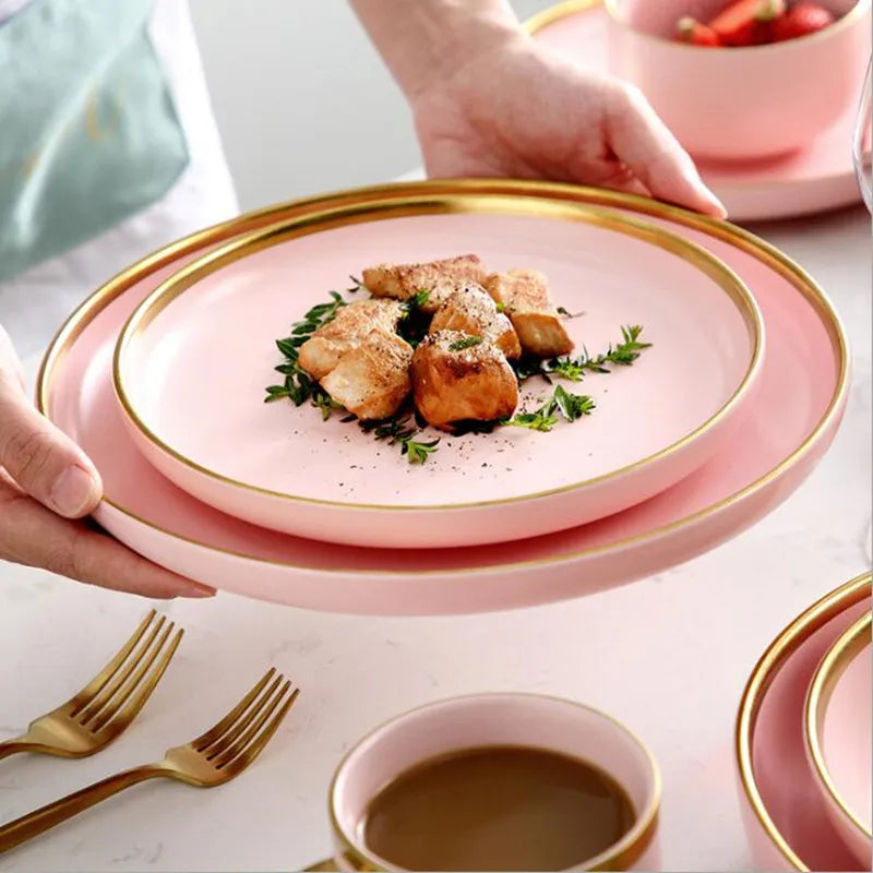 Pink porcelain dinner plate with gilt rim from MC The Black Diamonds, showcasing a ceramic food dish with detailed design.