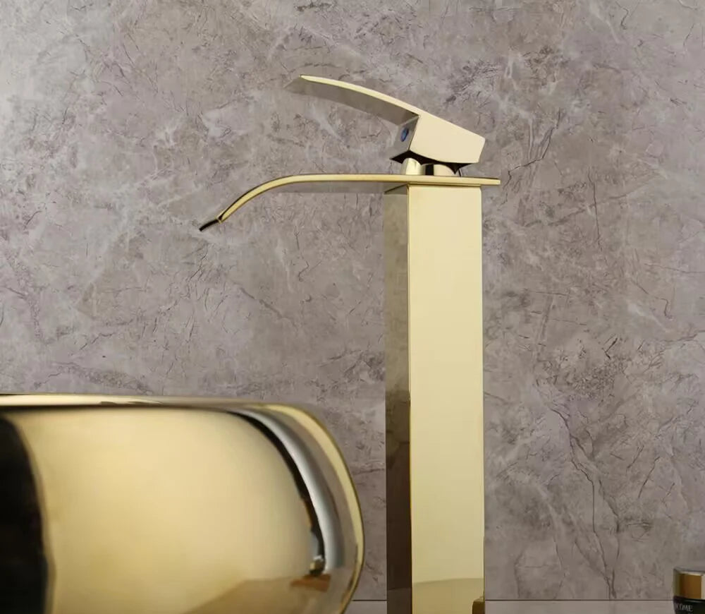 Luxury 23-inch oval ceramic bathroom vessel sink by MC THE BLACK DIAMOND with gold finish and waterfall faucet, above counter design.