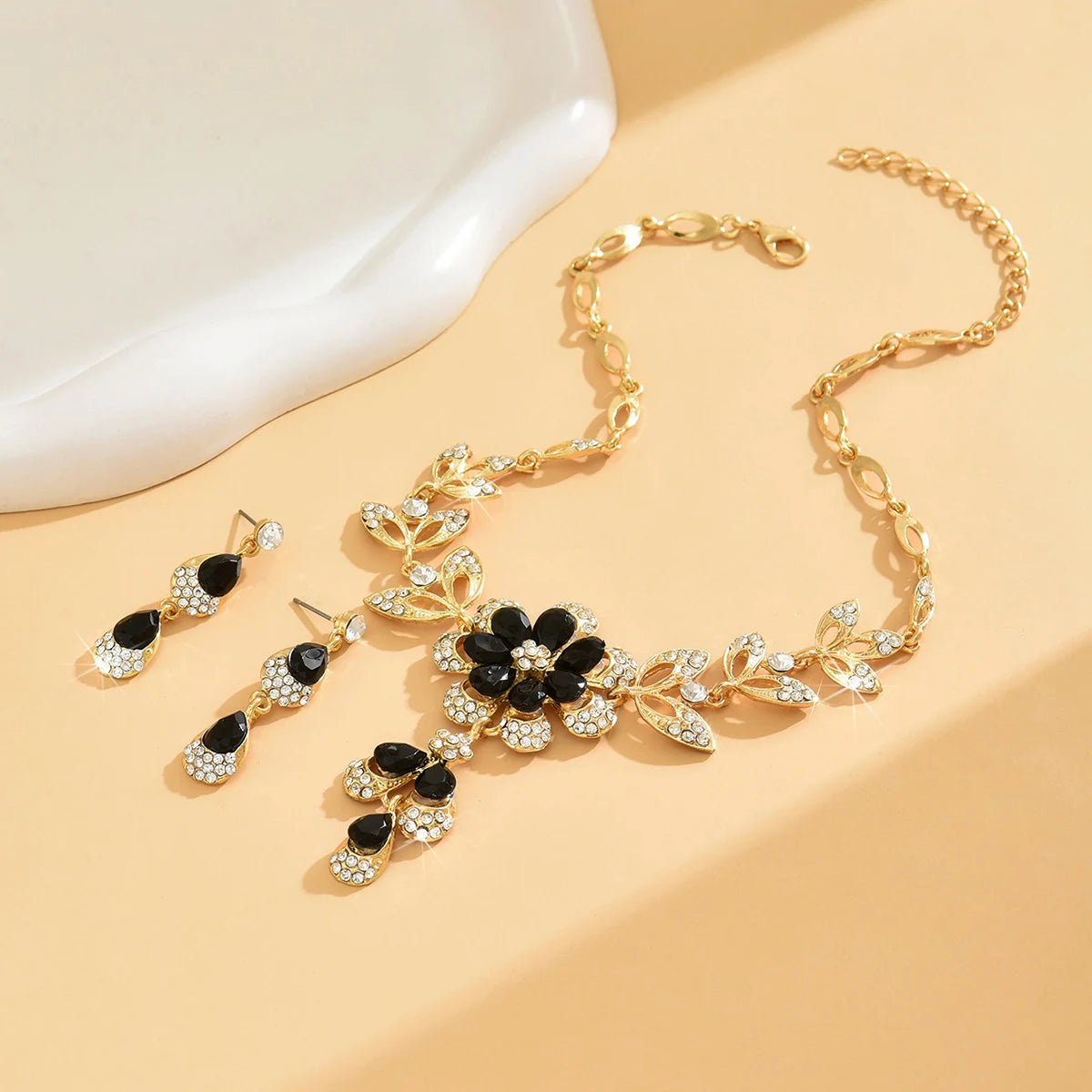 Three-piece women's black and gold flower necklace set by MC The Black Diamonds, featuring elegant floral pendant designs.