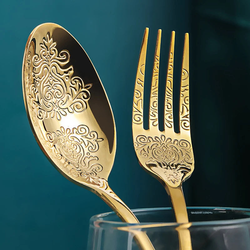 Set of 16/24 stainless steel silverware, gold cutlery kit from MC The Black Diamonds, includes forks, knives, spoons on a kitchen table.