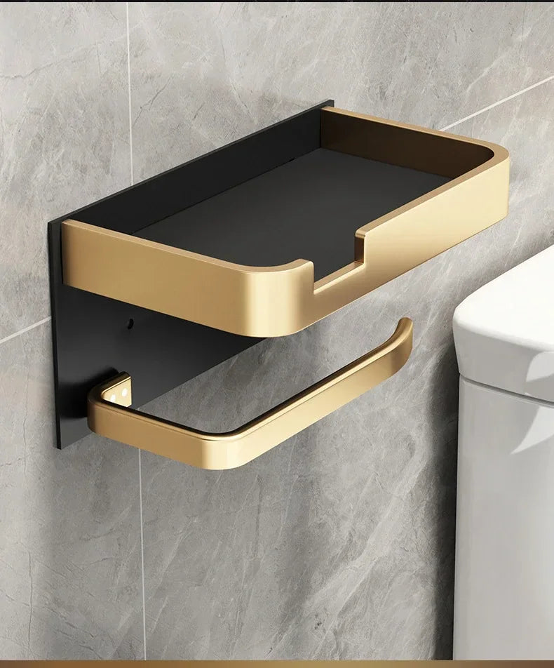 Black gold bathroom toilet paper holder by MC THE BLACK DIAMOND mounted on a bathroom wall with a roll of toilet paper.